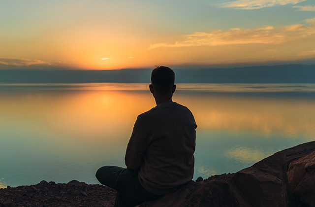 Young male contemplating the scenic sunset above the Dead Sea in Jordan